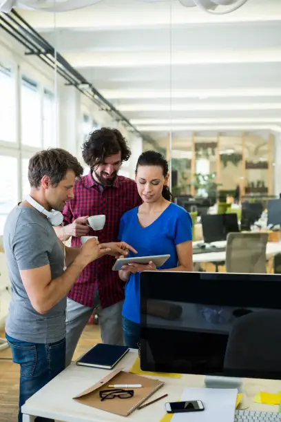 Group of graphics designers using digital tablet while having coffee